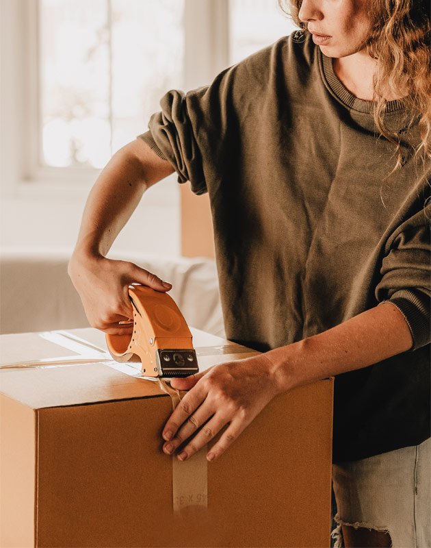 Frau verpackt Karton mit umweltfreundlicher Verpackung, symbolisiert RAU Cosmetics' Engagement für nachhaltige Produktverpackung.