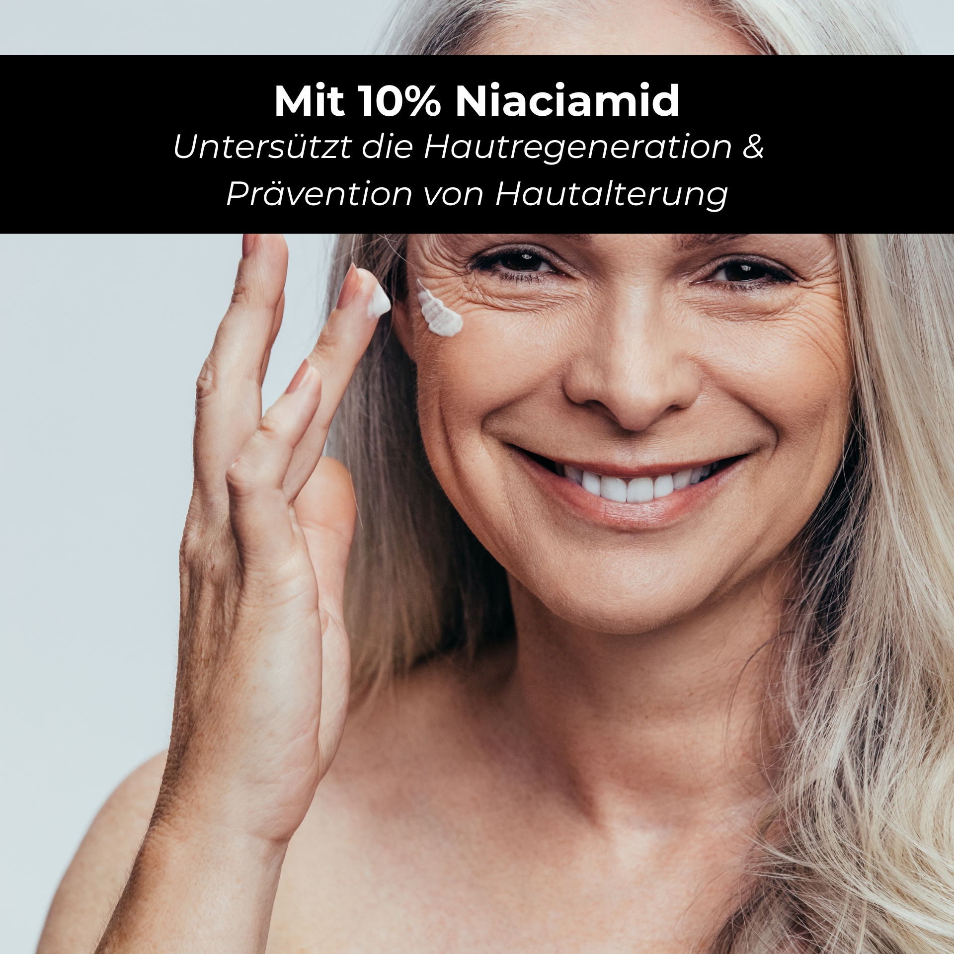 Niacinamide & Astaxanthin Serum 100 ml with 10% Niacinamide & 1% Zinc PCA Frau mit grauen Haaren, die Niacinamid-Creme auf ihr Gesicht aufträgt, unterstützt Hautregeneration und Altersprävention, mit Text: "Mit 10% Niacinamid".